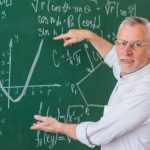 1655391370 senior teacher glasses explaining math example green chalkboard 1